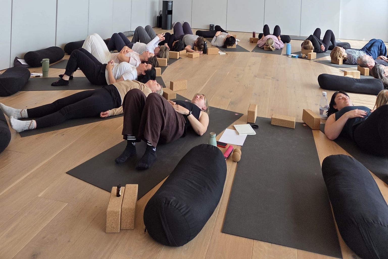 Retreat guests lying in constructive rest on mats with bolsters and cork blocks