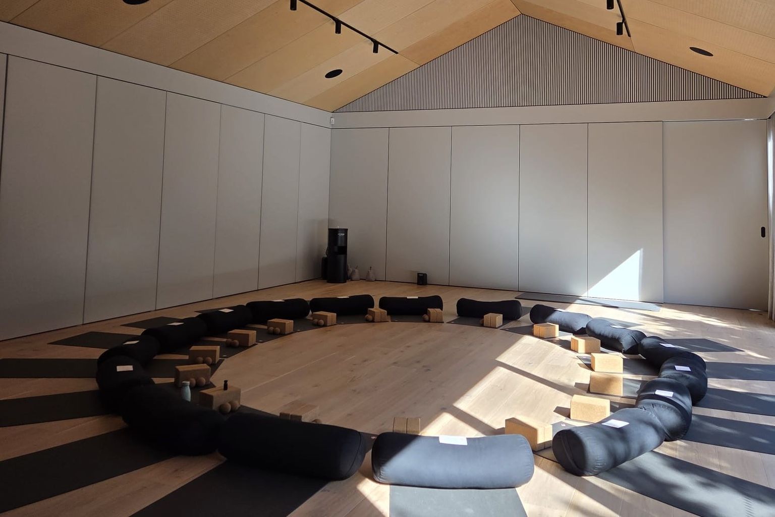 The retreat room set for a circle: bolsters, cork blocks and mats on timber floors under a timber ceiling